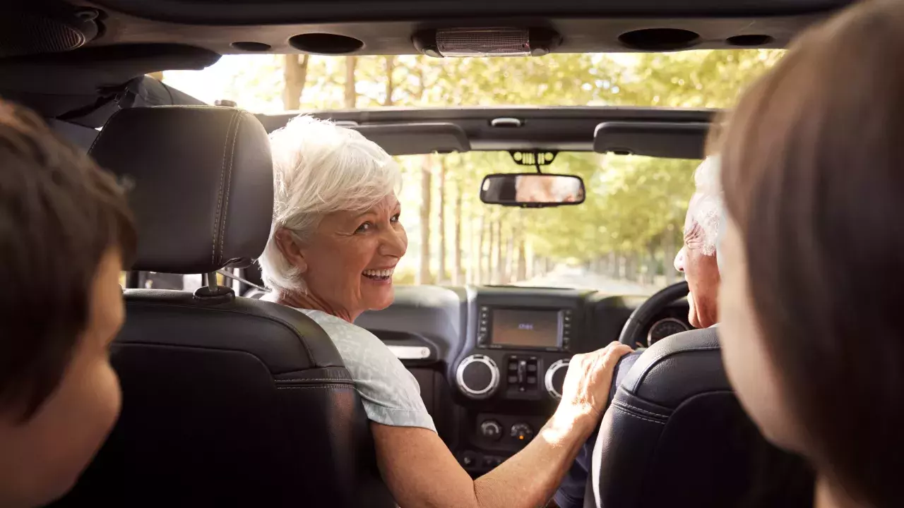 Grandparents And Grandchildren Driving In Open Top Car