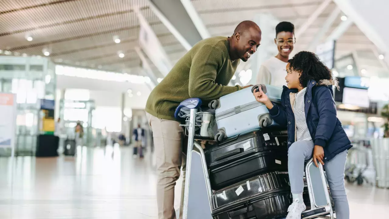 Family laughing together with all their luggage in an airport. 