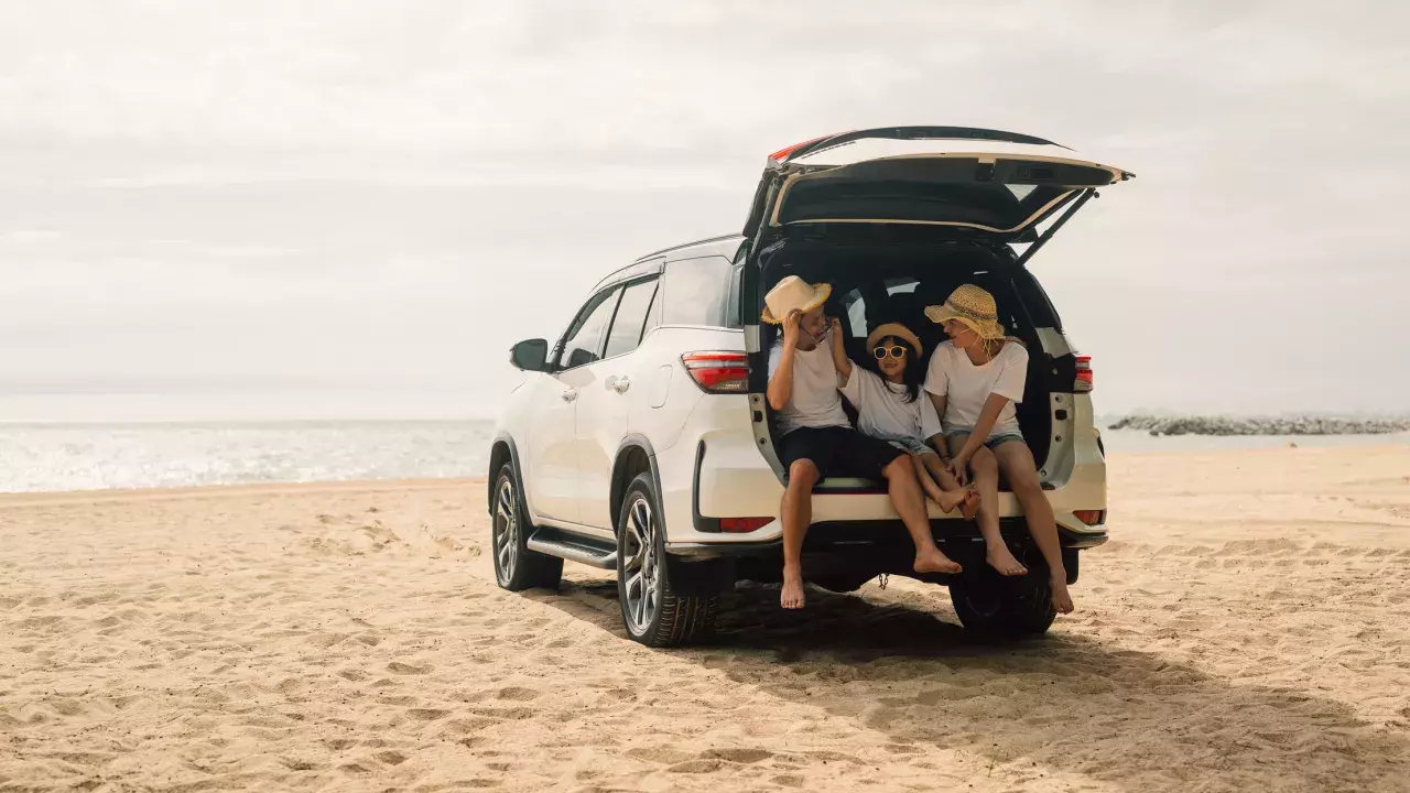 Family sitting in the trunk of their car on the beach