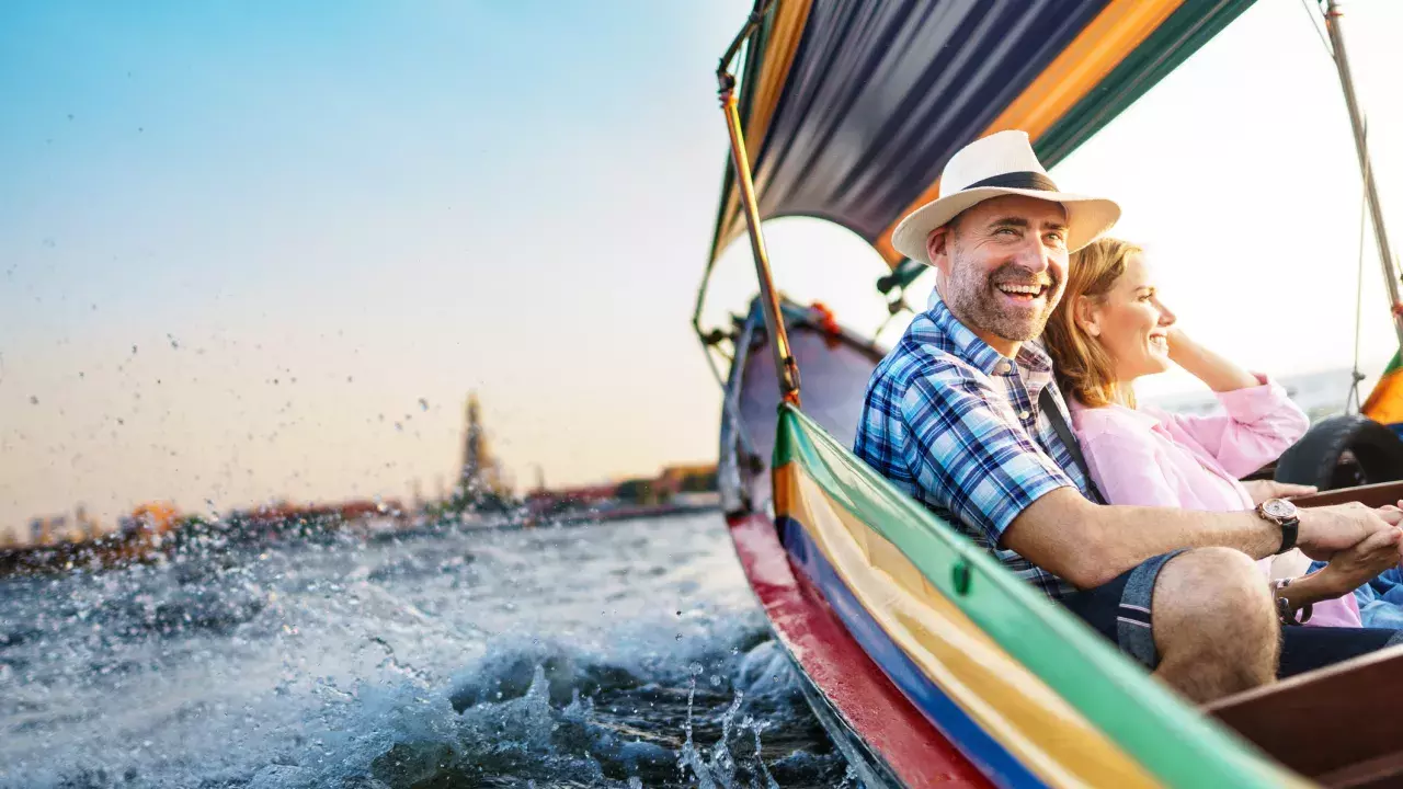 Couple smiling together as they ride in a small boat. 