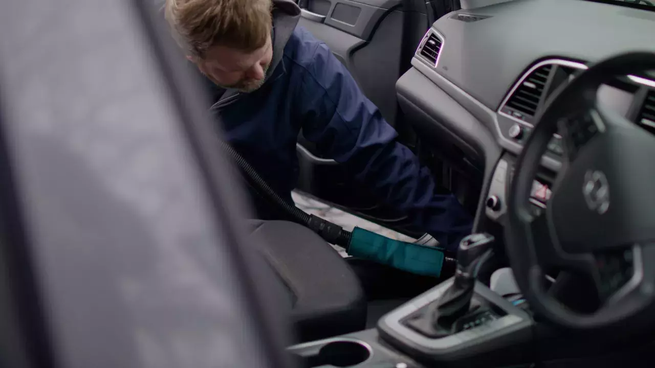 technician is detailing the interior of a vehicle