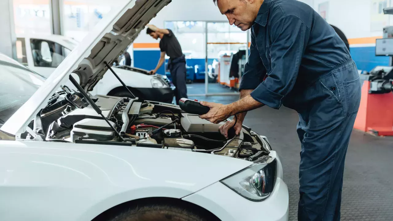 worker checking a car battery in auto garage