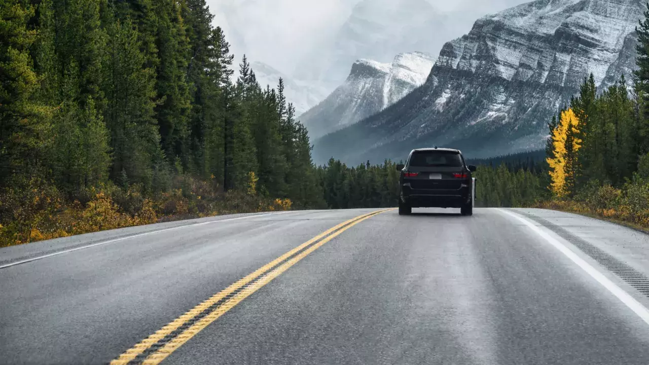 Car driving along the road with trees and mountains in the distance