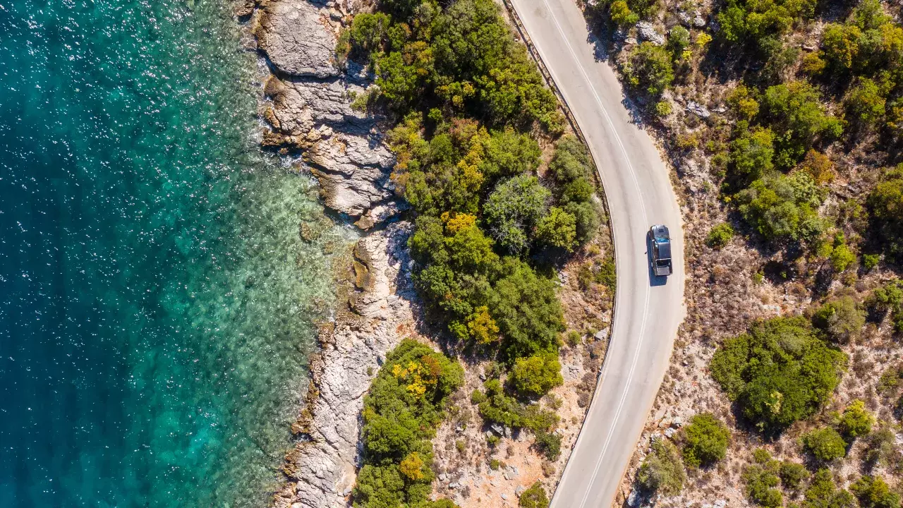 Car driving along the road with trees and water