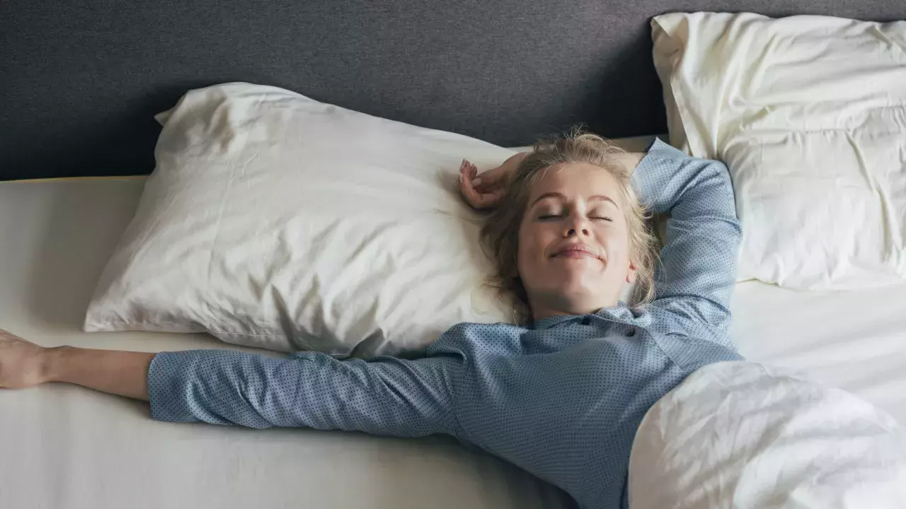 Woman laying in a hotel bed wearing pjs