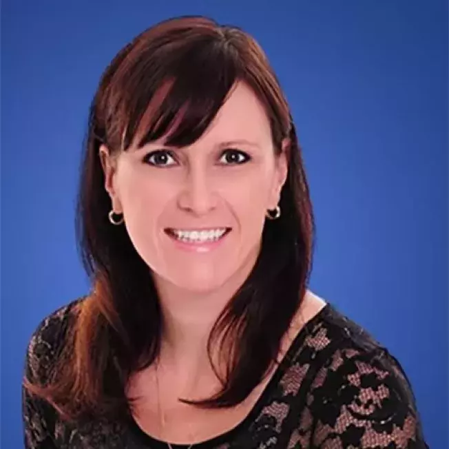 professional headshot of a woman smiling at the camera infront of a blue backdrop