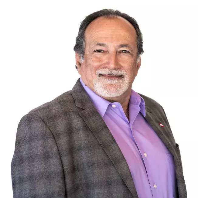 professional headshot of a mane smiling at the camera infront of a white backdrop