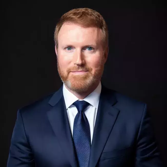 Professional headshot of a white man in front of a white backdrop