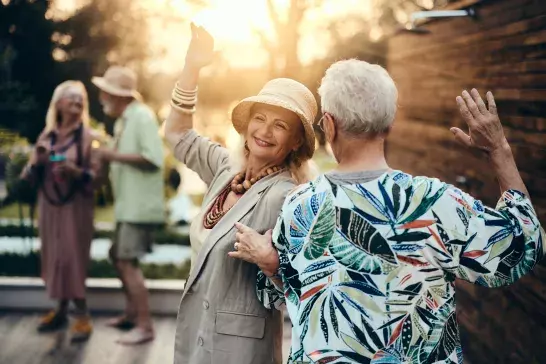 Happy couple having fun while spinning and dancing during a party in the backyard at sunset.