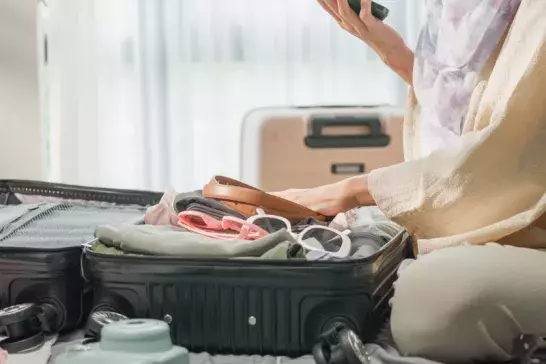 Woman packing a suitcase while looking at her phone