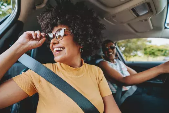 Two women driving in a car on a road trip 