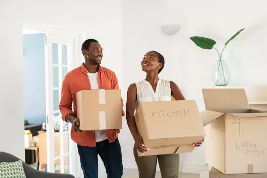 Adult couple moving cardboard boxes into new home