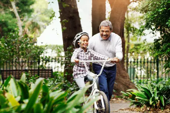 Grandfather teaching grandson how to ride a bike at the park