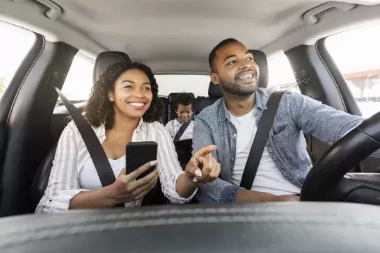 Positive black family have car ride, using smartphone for navigation stock photo