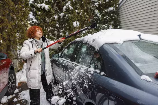 Woman cleaning snow off her car