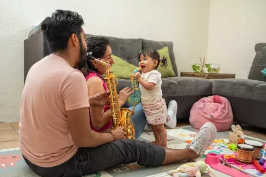 Mother and father playing musical instruments with toddler