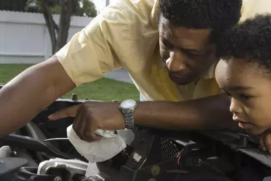 Father and son (5-6) repairing car's engine