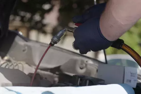 Hands under the hood of a vehicle doing an oil change