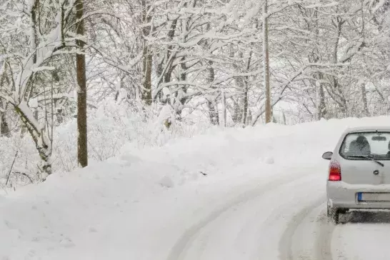 car driving on a winter road in forest