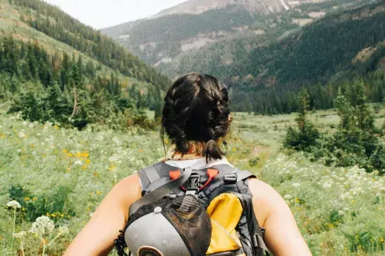 Woman hiking in a field with flowers 