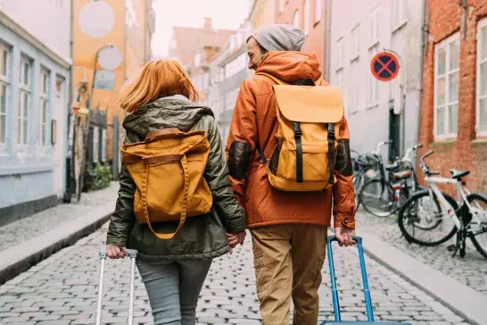 Couple walking with suitcases through an empty street