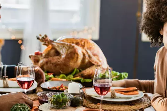 Happy black family talking during Thanksgiving meal at dining table.