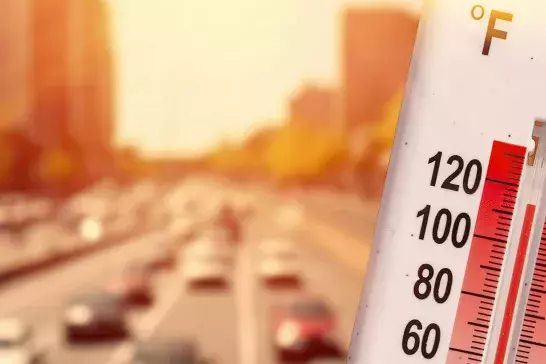 Thermometer in front of cars and traffic during heatwave