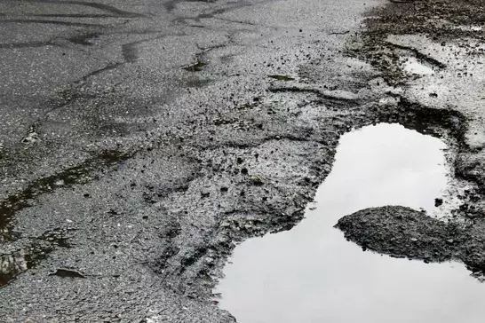 Cracked and pothole-ridden pavement.