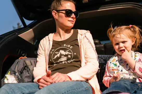 A mother and a daughter sitting in a trunk happily