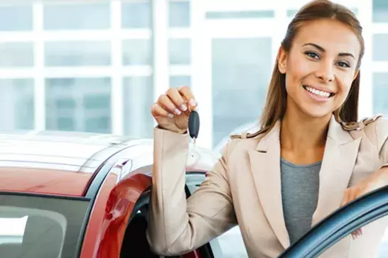 woman smiling next to a new car holding keys 