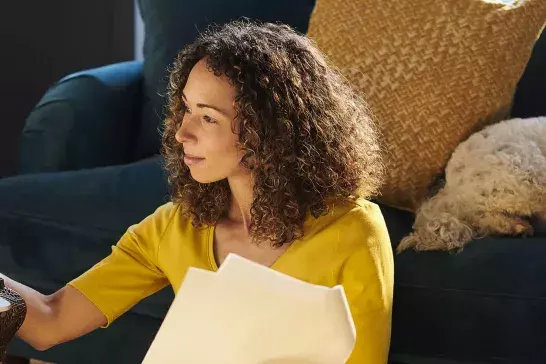 Woman reviewing her pet insurance paperwork while her dog sleeps on the couch