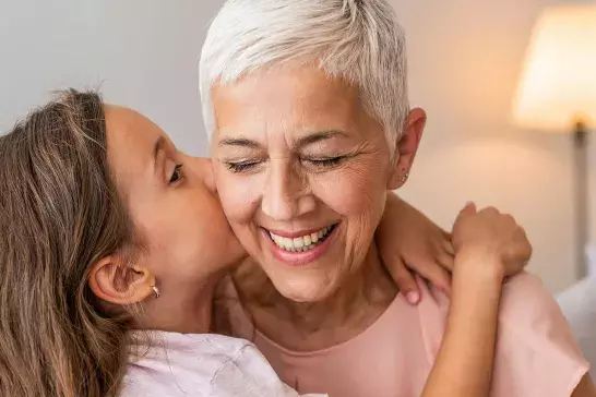 Grandmother and granddaughter hugging.