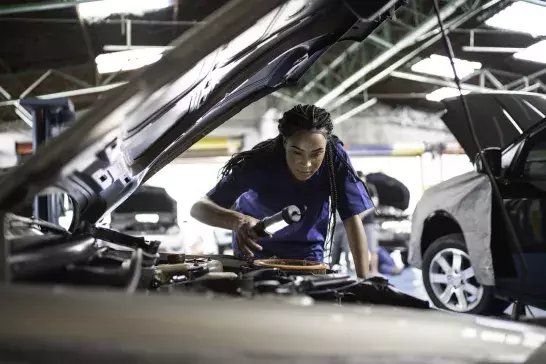 Woman repairing a car in auto repair shop