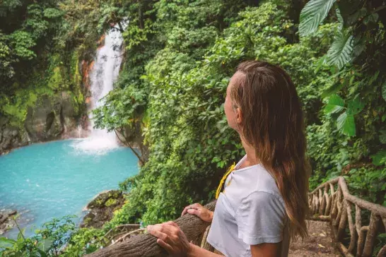 Young woman contemplating turquoise waterfall in Costa Rica