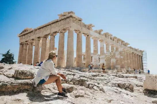 Woman relaxing while looking at Parthenon temple against clear sky