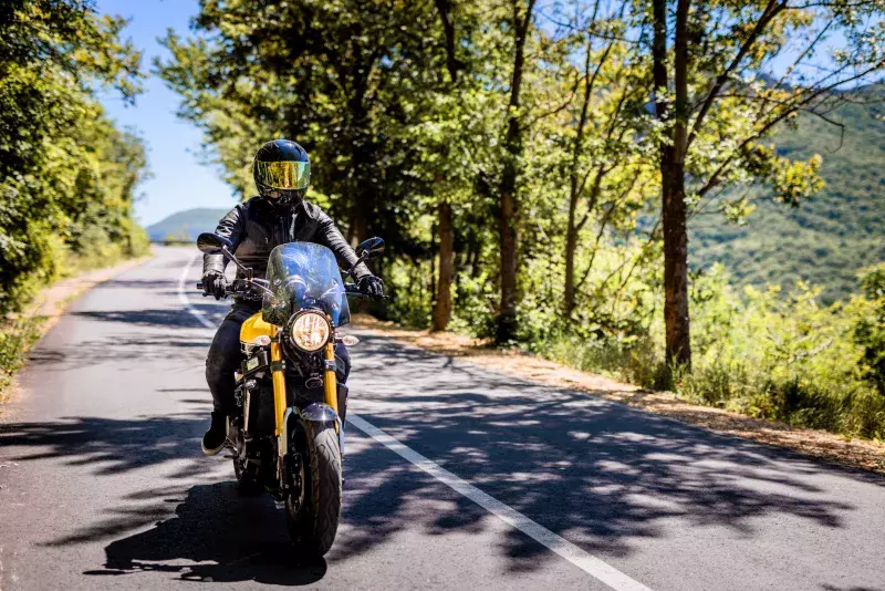 Biker with full safety gear enjoys ride on country road