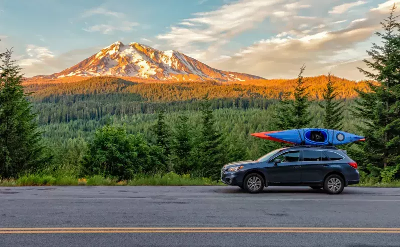 Subaru with kayaks at the top of the vehicle on the road