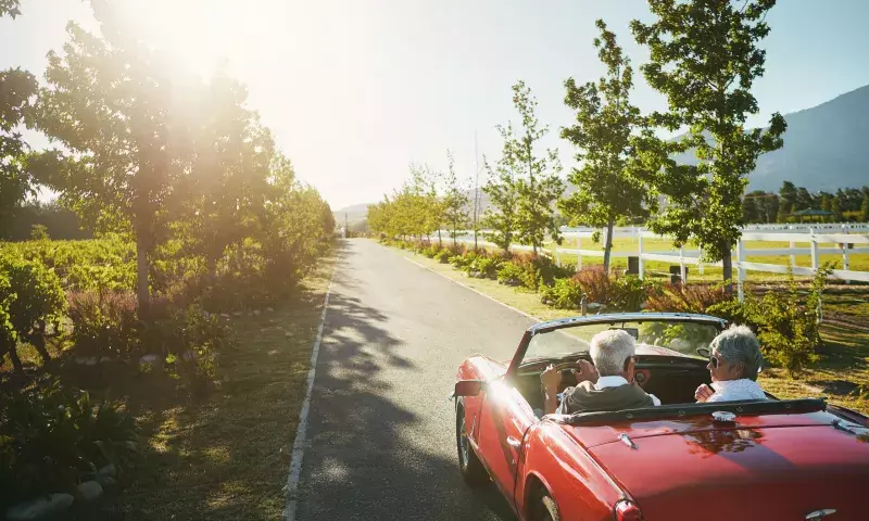 Couple, convertible and driving road trip or travel journey in vineyard, adventure or transportation. People, nature and tourism holiday for explore together in retirement,