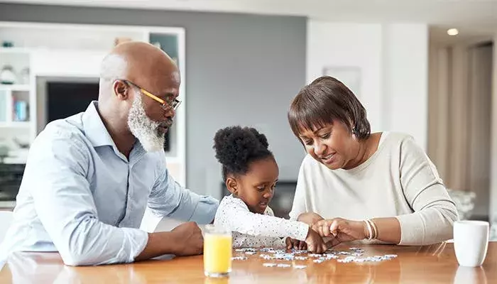 Grandparents doing a puzzle with granddaughter