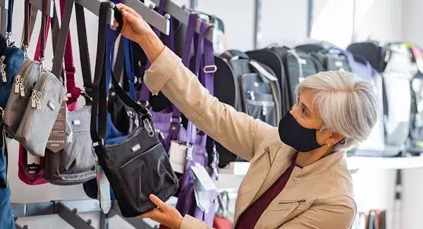 CAA Member browsing purses at CAA Store with face mask on