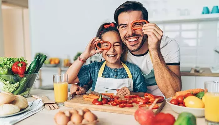 Father and daughter having fun in the kitchen preparing fresh vegetables