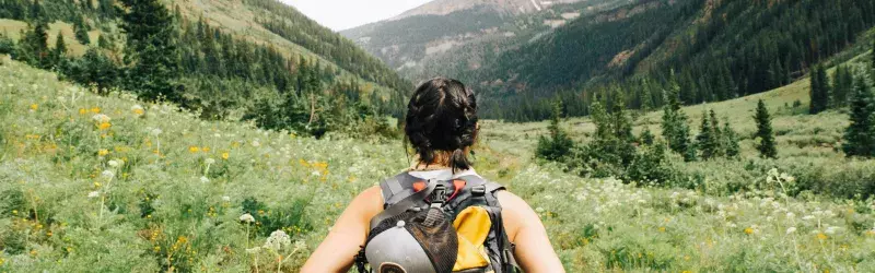 Woman hiking in a field with flowers 