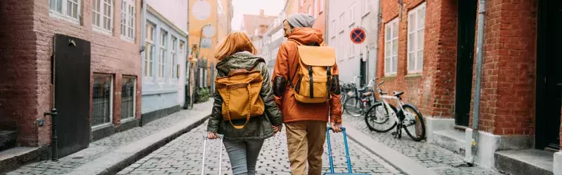 Couple walking with suitcases through an empty street