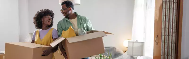 Couple moving boxes into their apartment