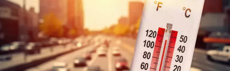 Thermometer in front of cars and traffic during heatwave