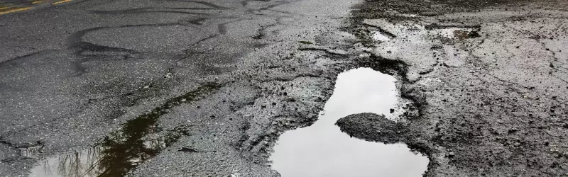 Cracked and pothole-ridden pavement.