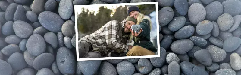 A couple are nestled together and the girl hold a heart shaped stone in hand