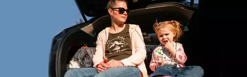 A mother and a daughter sitting in a trunk happily