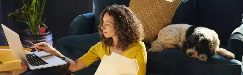 Woman reviewing her pet insurance paperwork while her dog sleeps on the couch