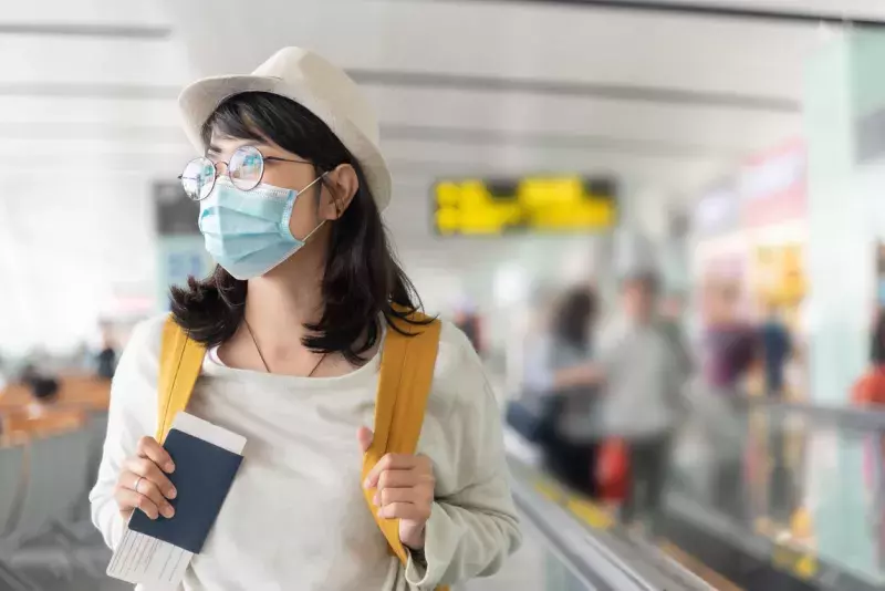 Woman holding passport in the airport wearing a mask